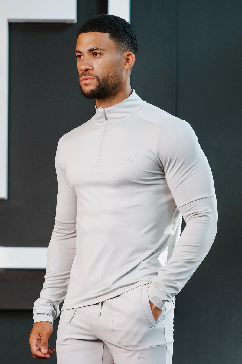 Man wearing a light grey, long-sleeve athletic pullover with a half-zip collar